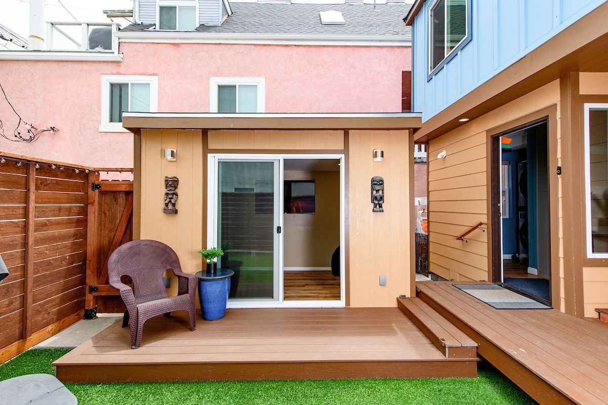 A patio with a chair and a potted plant in front of a house.