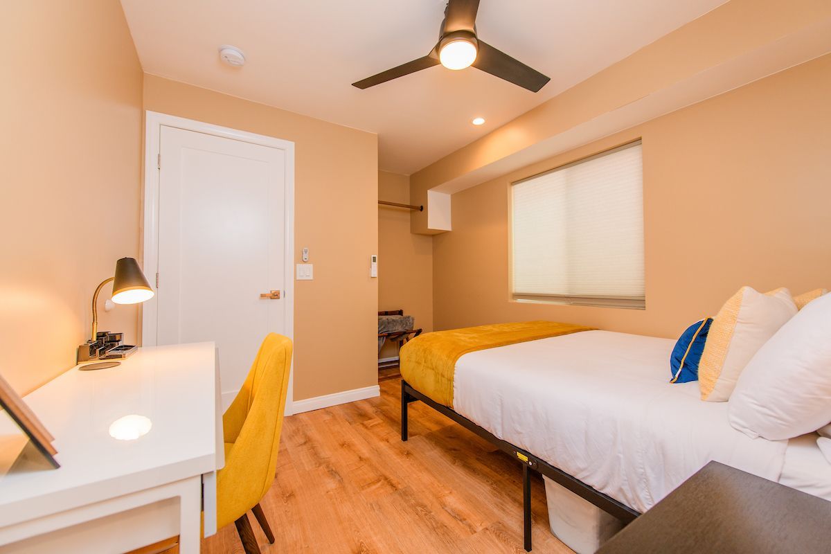 A bedroom with a bed , desk , chair and ceiling fan.