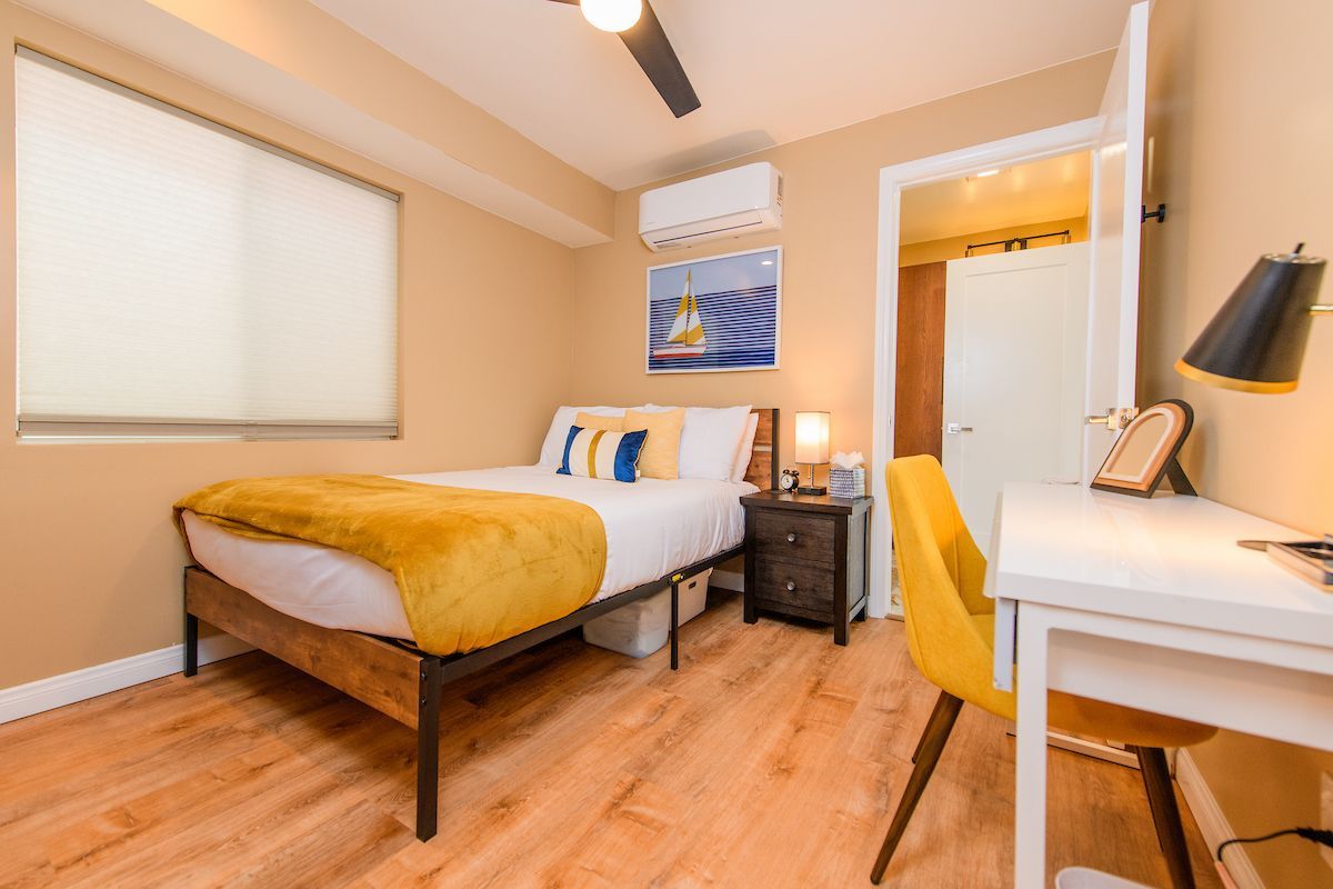 A bedroom with a bed , desk , chair and ceiling fan.