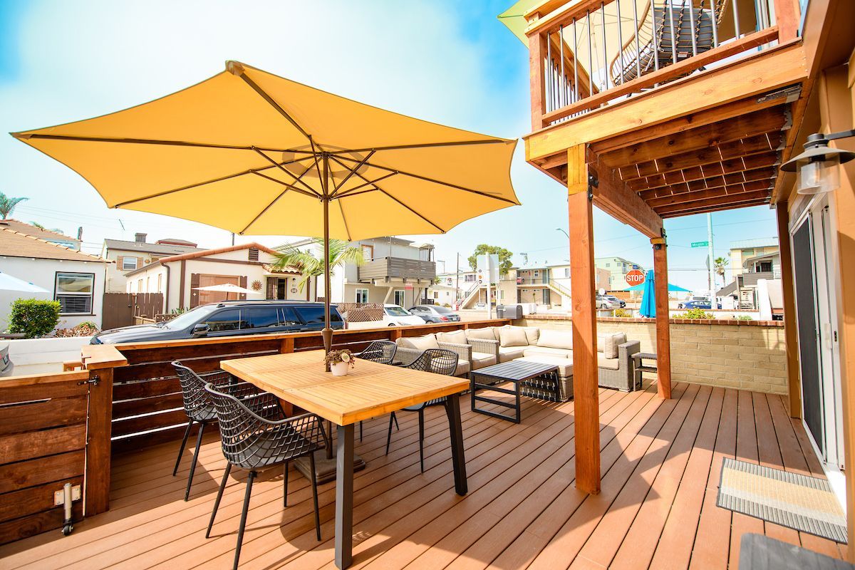 A wooden deck with a table and chairs and an umbrella.