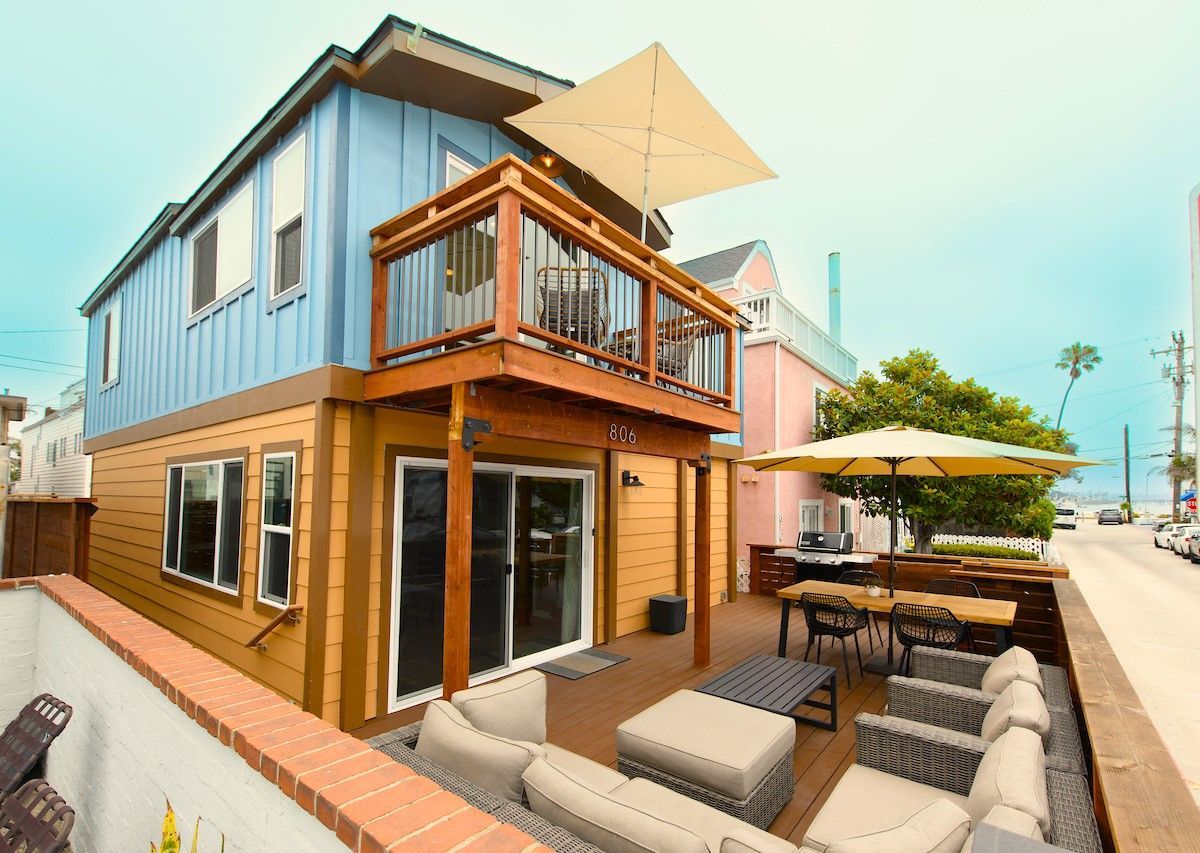 The front of a house with a large deck and umbrellas.