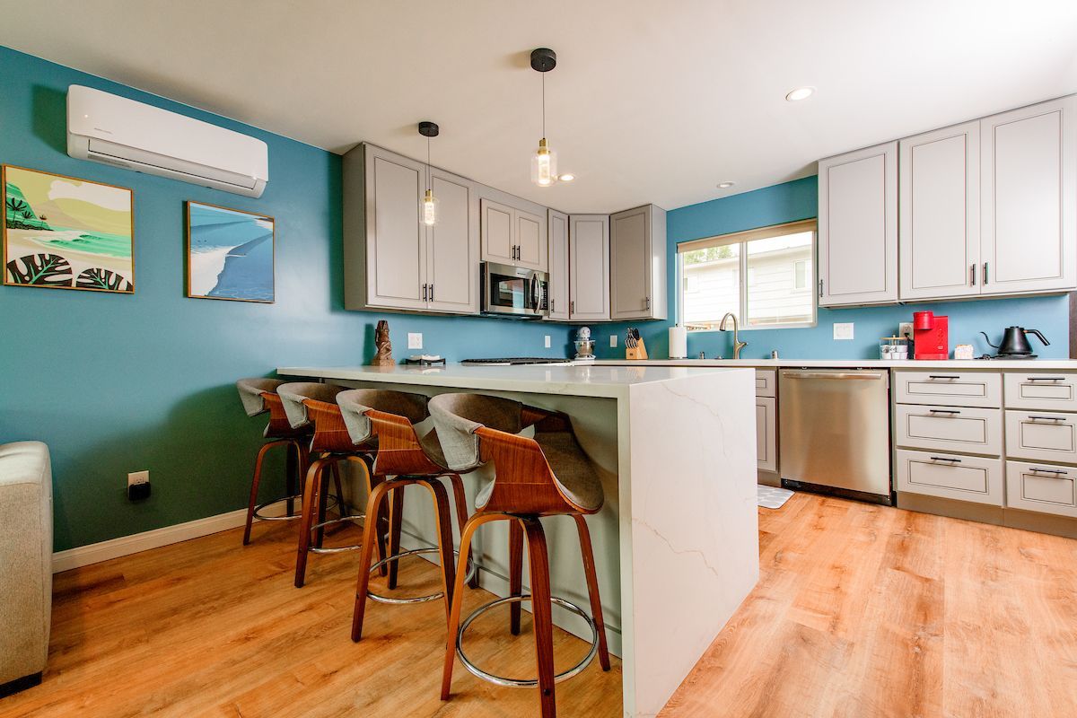 A kitchen with stools and a large island in the middle of the room.