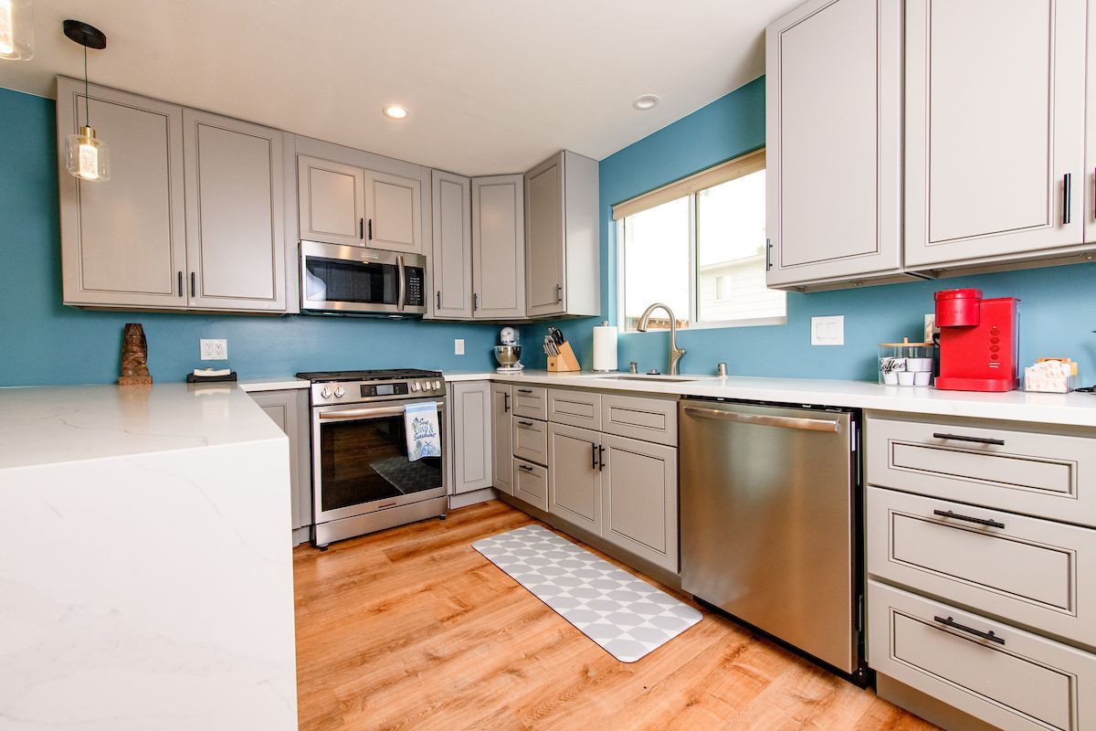 A kitchen with gray cabinets and stainless steel appliances.