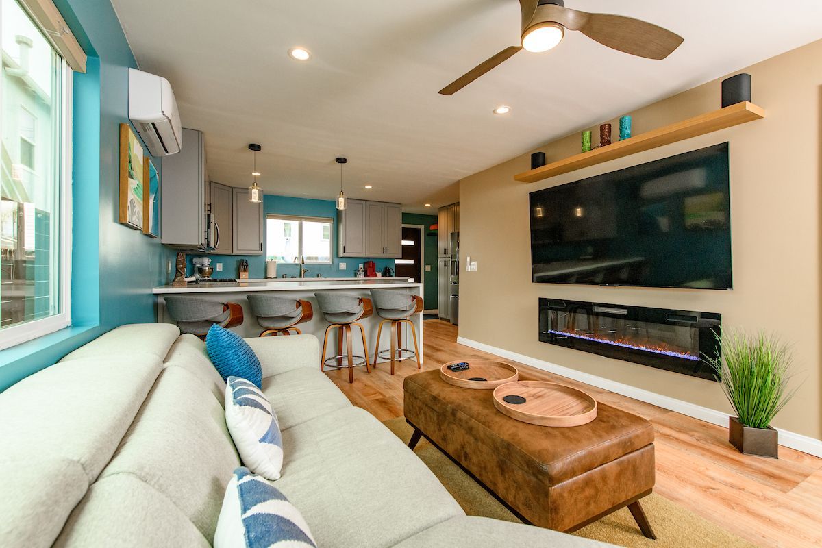 A living room with a couch , ottoman , television and ceiling fan.