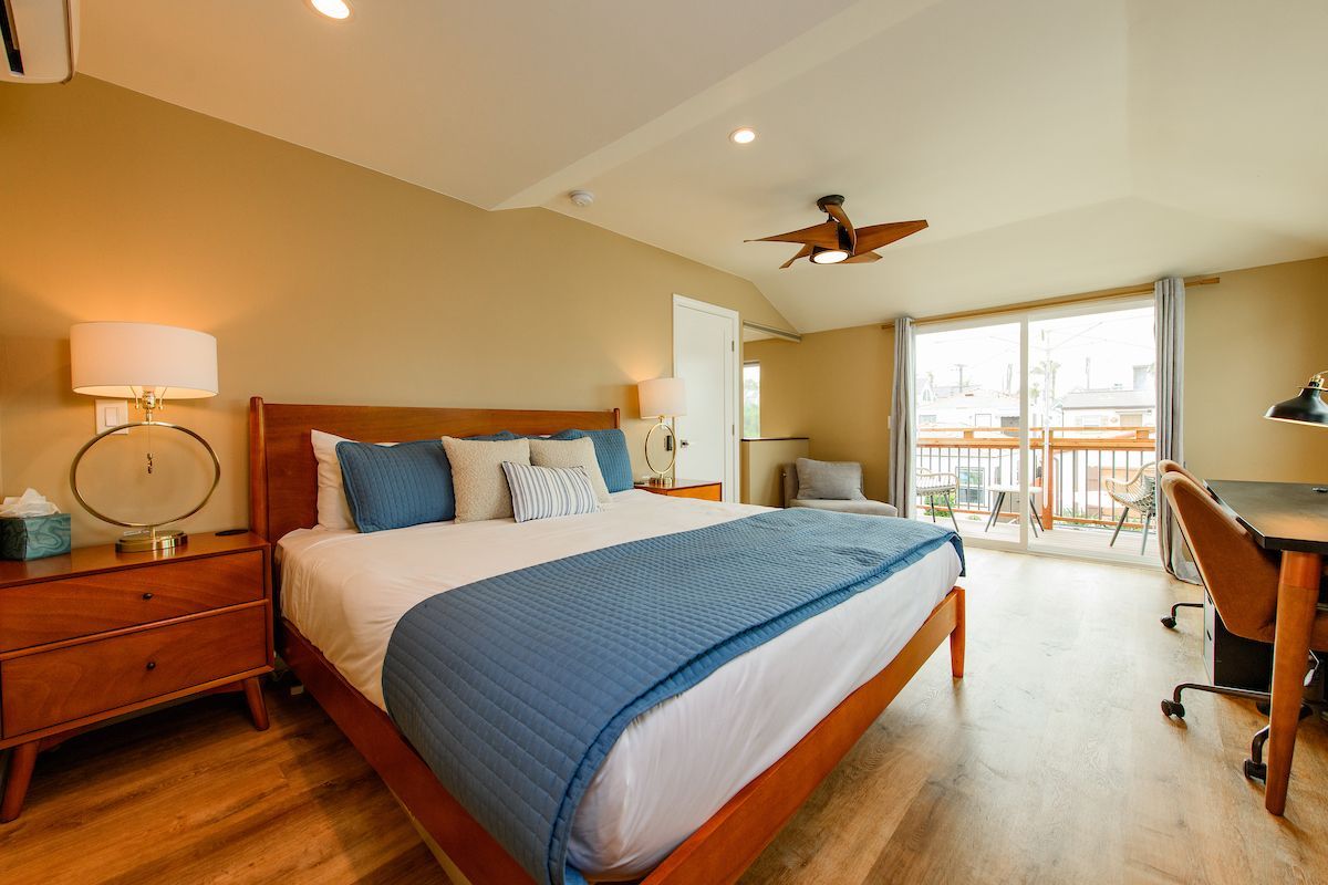 A bedroom with a king size bed , desk , nightstand and sliding glass doors.