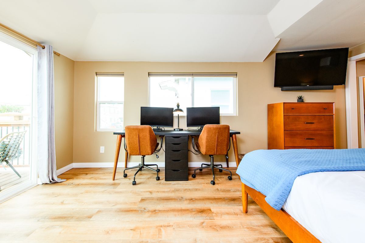 A bedroom with a bed , desk , chairs and a flat screen tv.