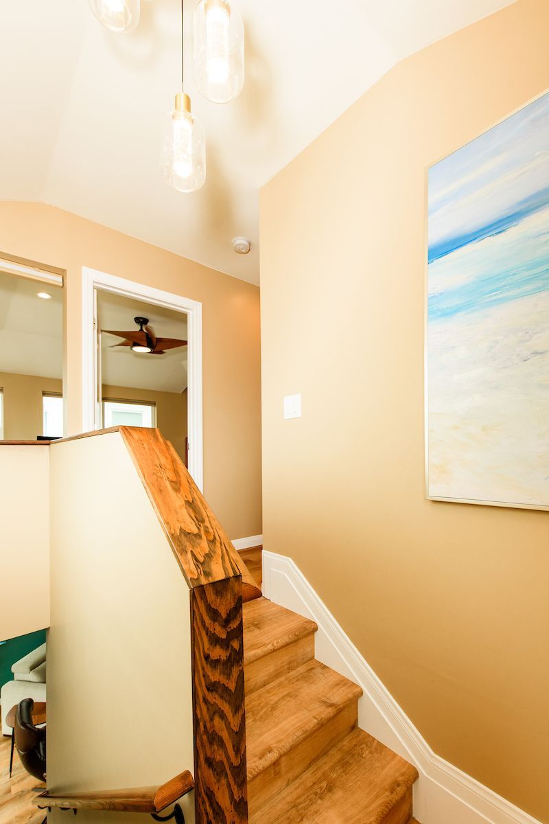 A wooden staircase with a painting on the wall above it