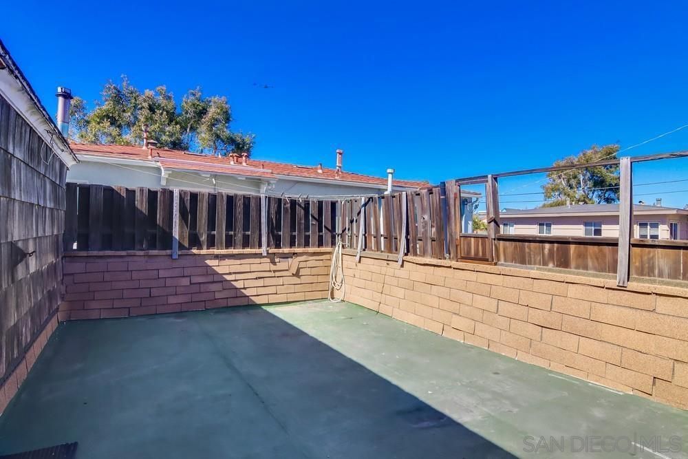 A patio with a brick wall and a fence in front of a house.