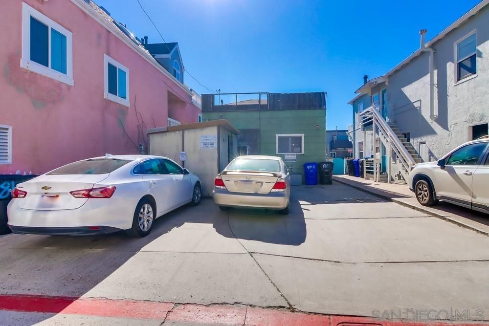Two white cars are parked in front of a pink building.