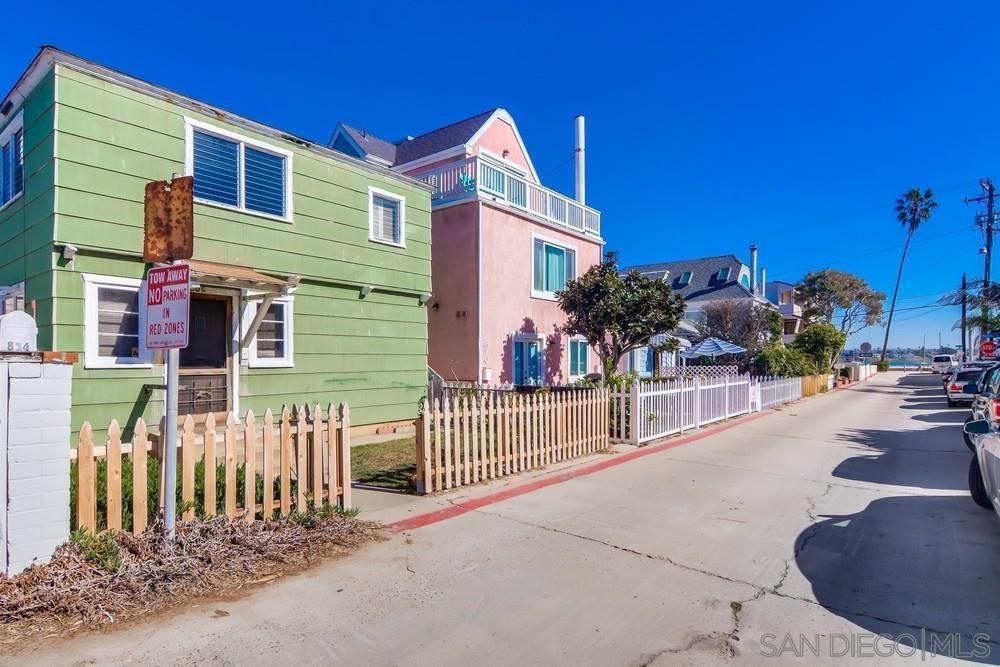 A green house and a pink house are next to each other on a street.