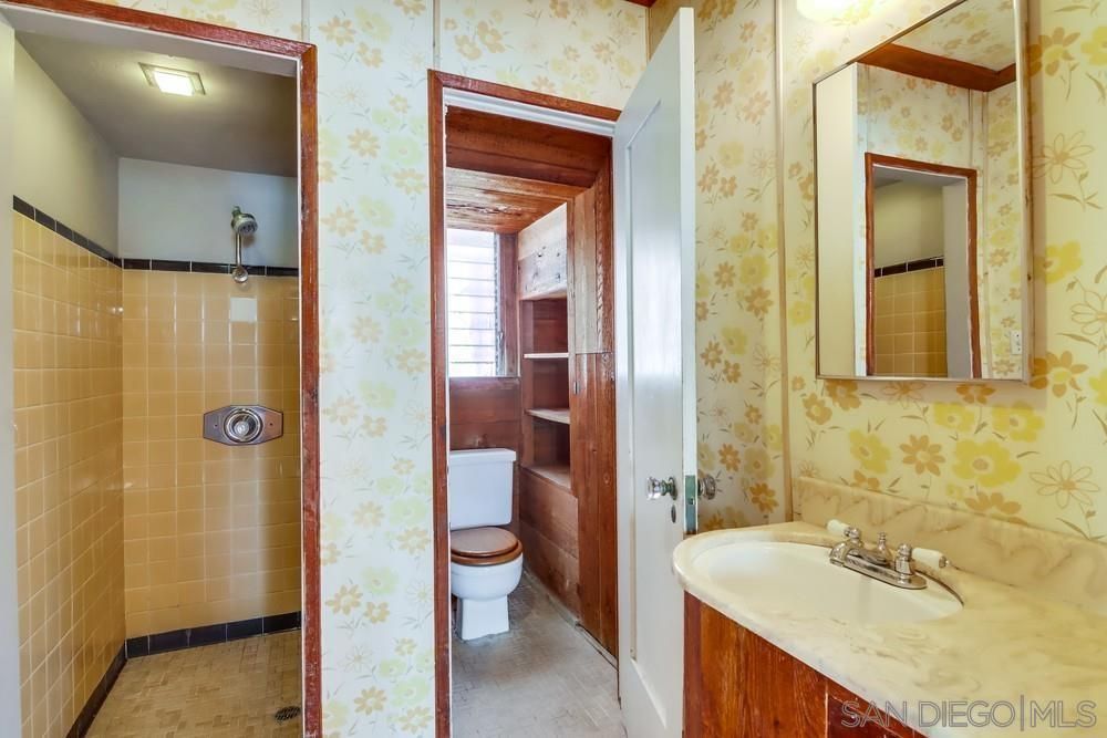 A bathroom with a toilet , sink , mirror and shower.