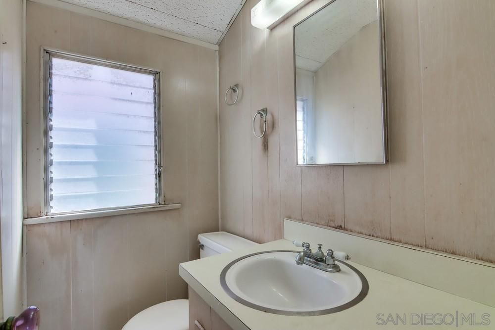 A bathroom with a sink , toilet , mirror and window.