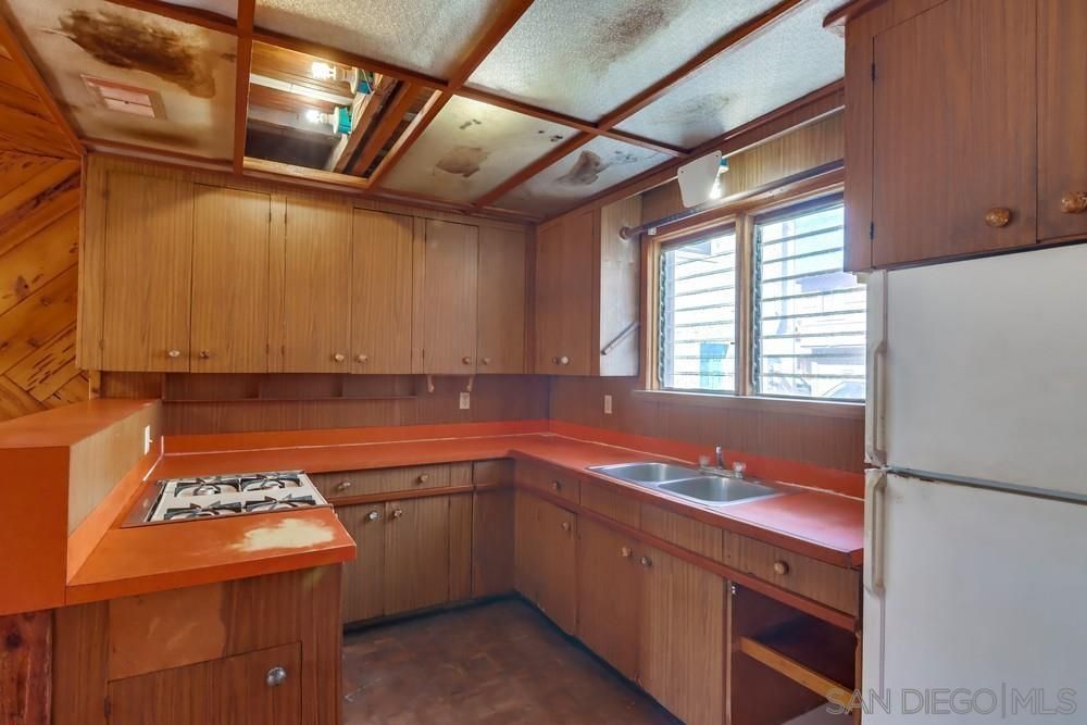 An empty kitchen with wooden cabinets and a white refrigerator