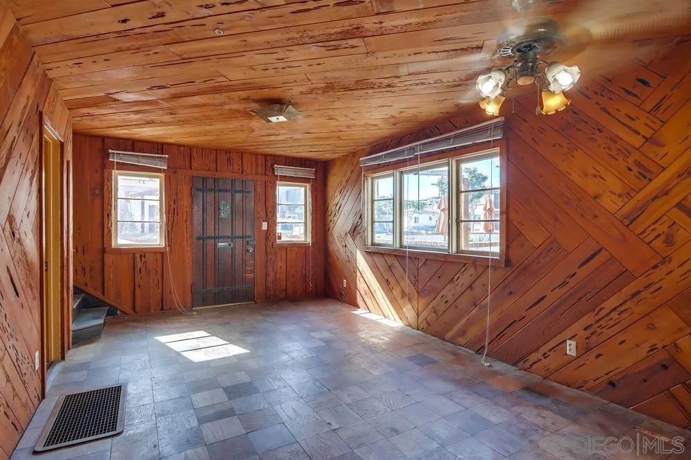 An empty room with wood paneling and a ceiling fan