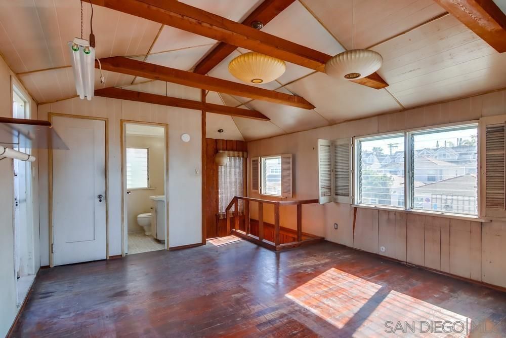 An empty room with a wooden floor and a ceiling fan.