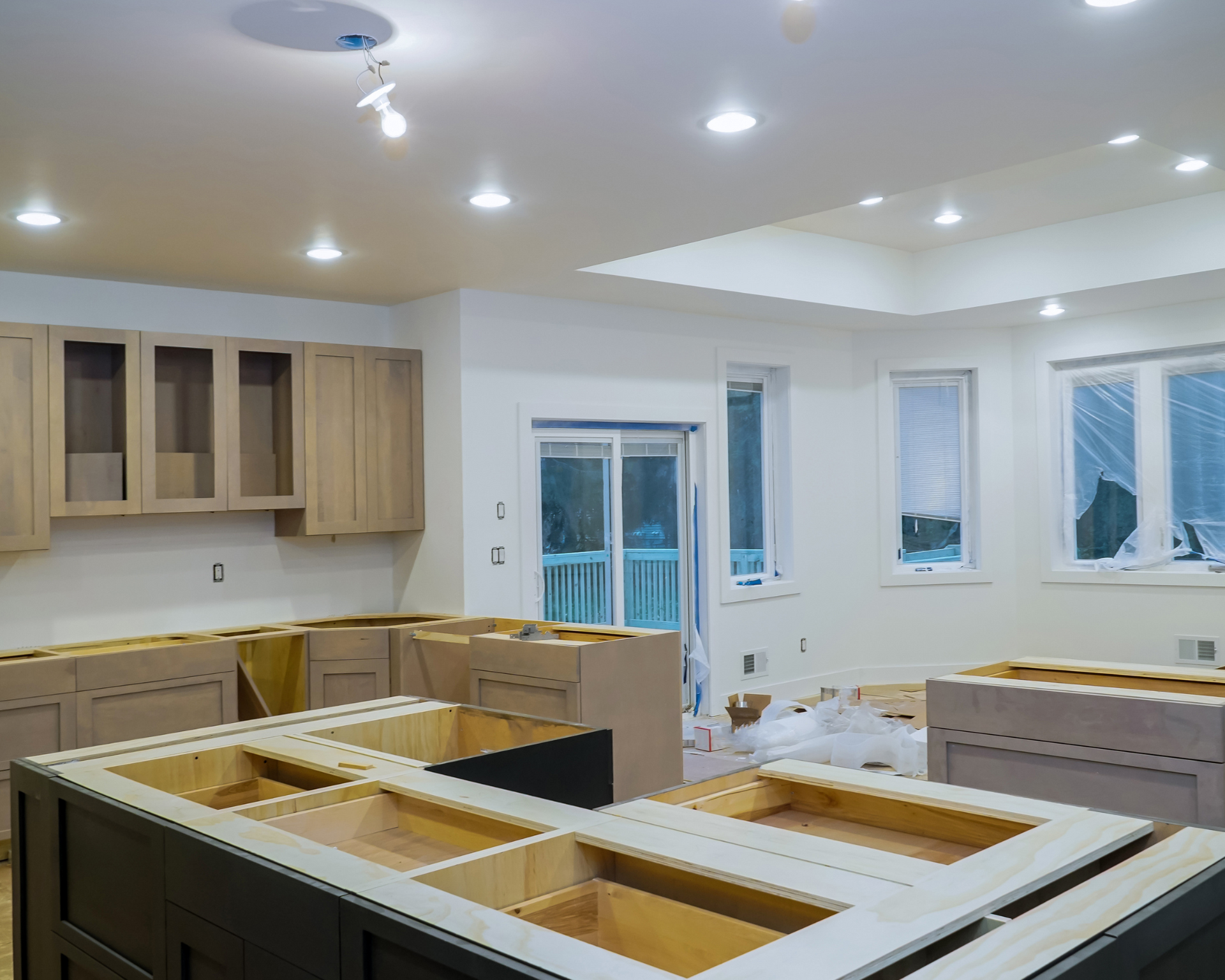 Kitchen under construction with unfinished cabinetry and recessed lighting.