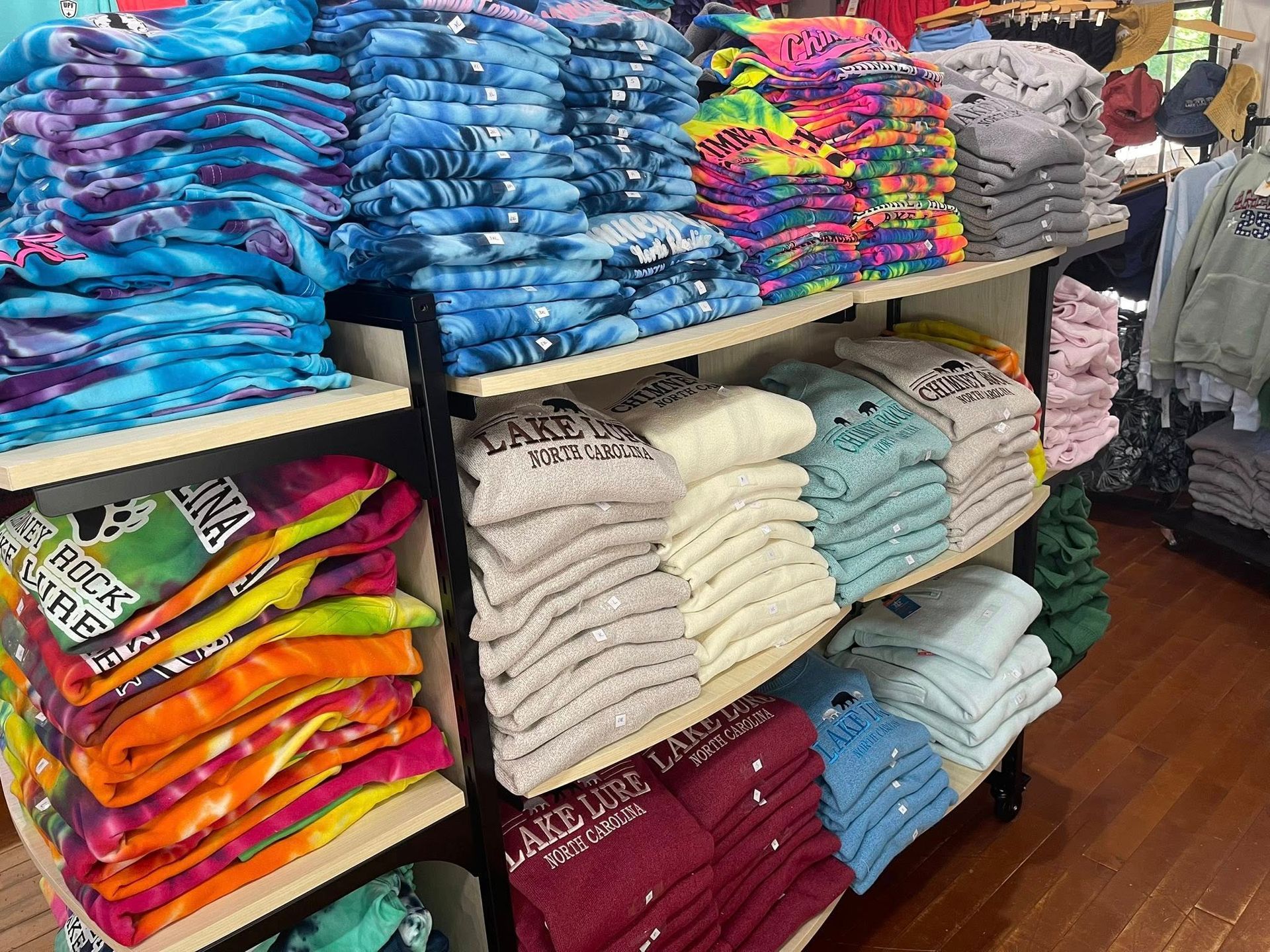 Warm gift shop interior with embroidered apparel and Chimney Rock souvenirs on rustic displays.