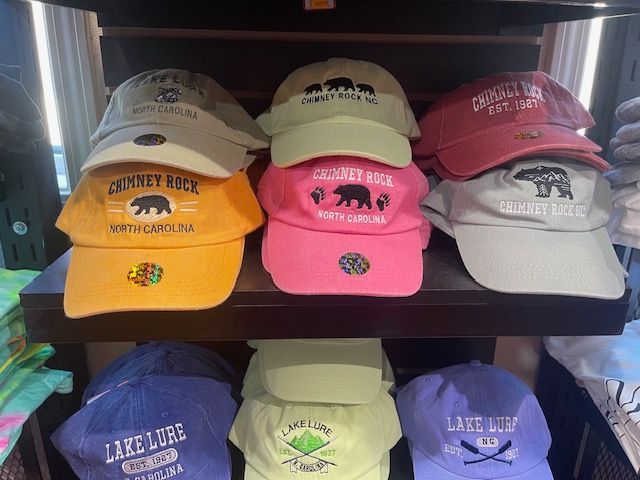 Embroidered caps and beanies with rustic mountain and local destination branding on display shelves.