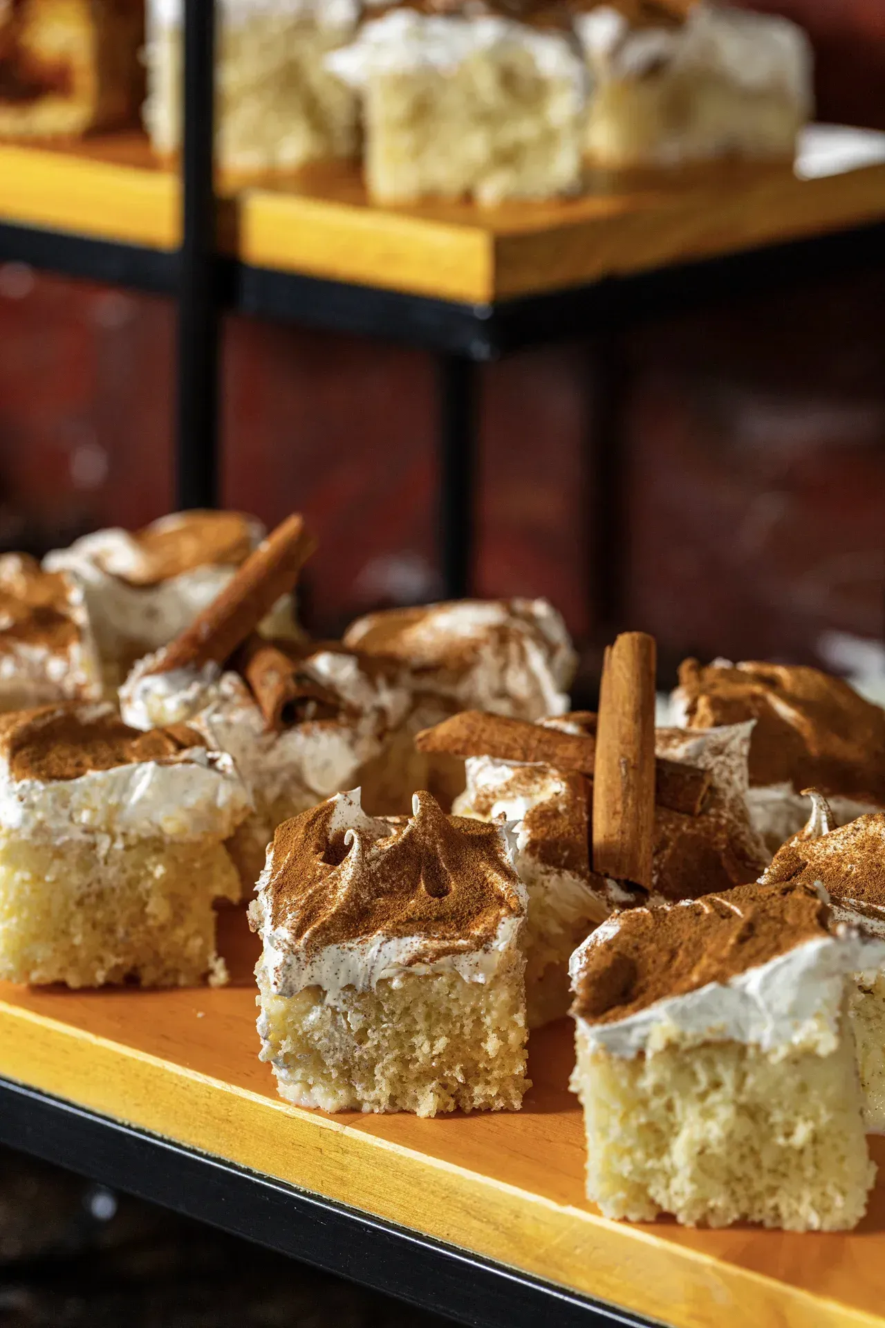 Uma prateleira de madeira cheia de fatias de bolo e paus de canela.