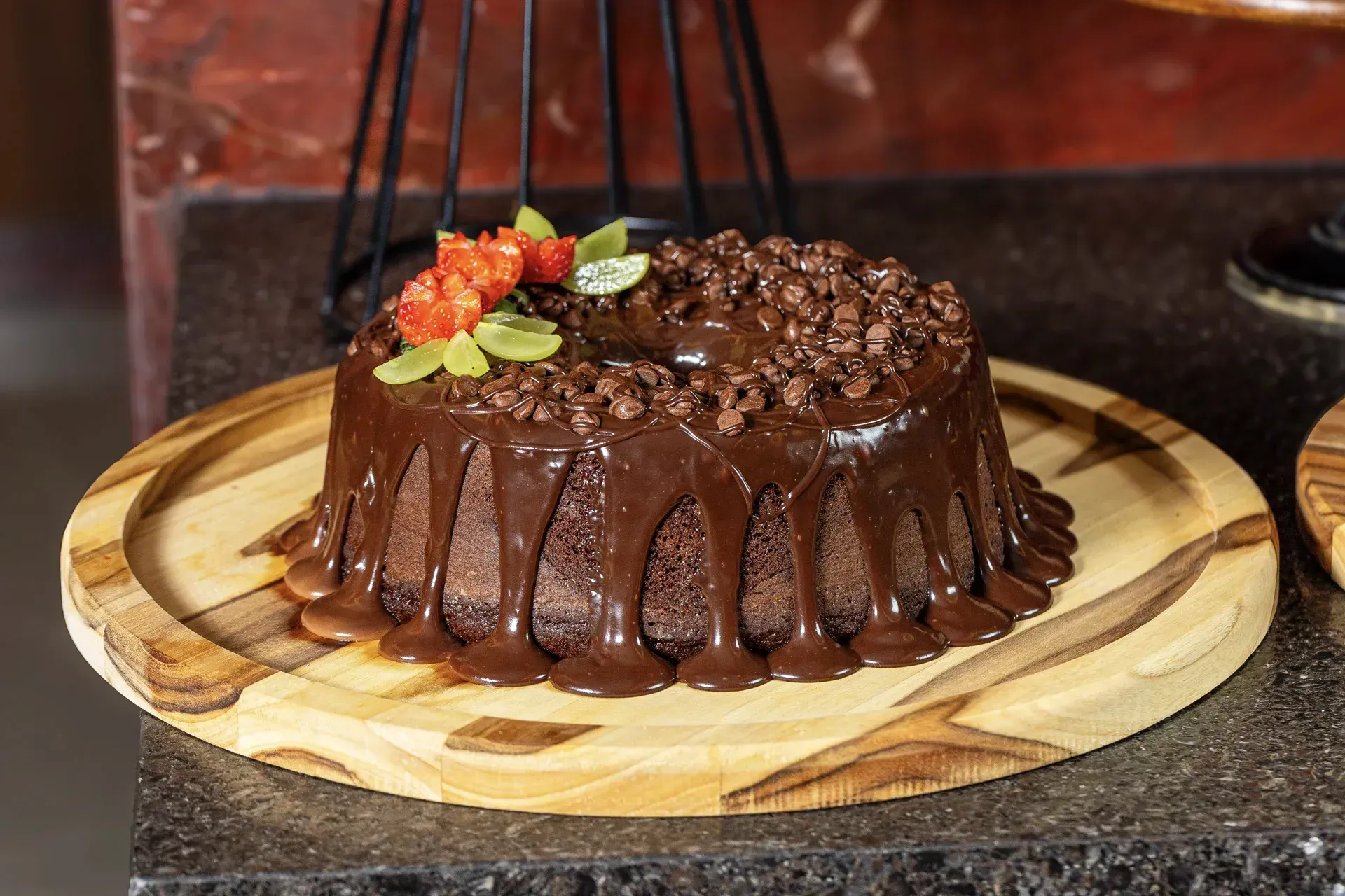 Um bolo de chocolate está sobre uma tábua de corte de madeira.