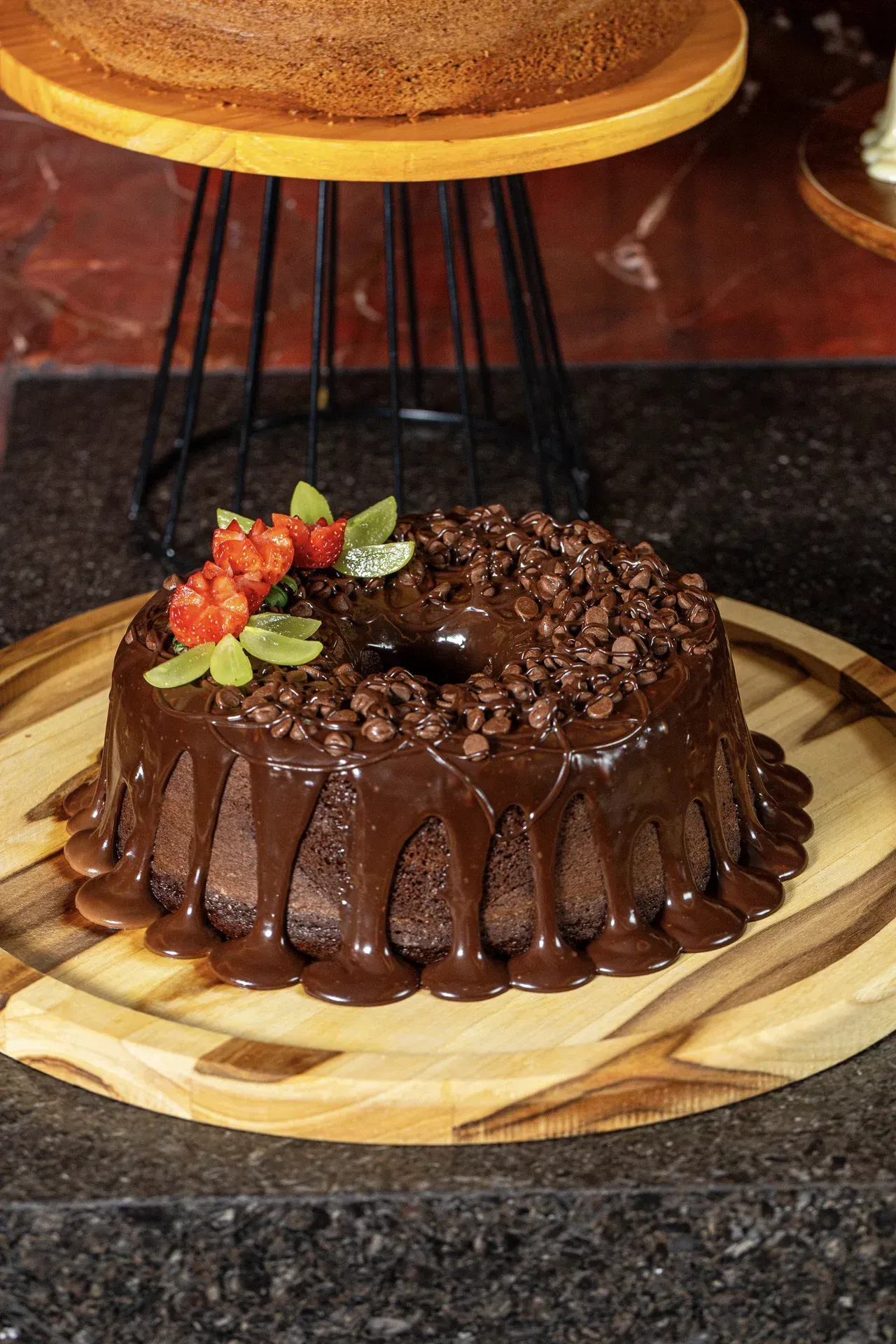 Um bolo de chocolate está em cima de uma tábua de corte de madeira.