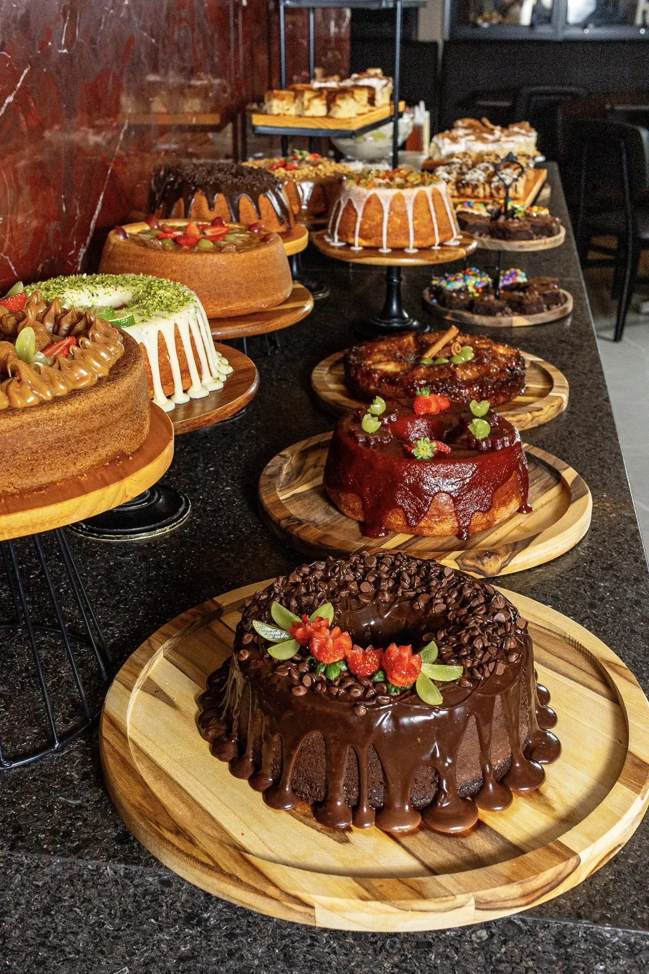 Uma mesa coberta com uma variedade de bolos em bandejas de madeira.