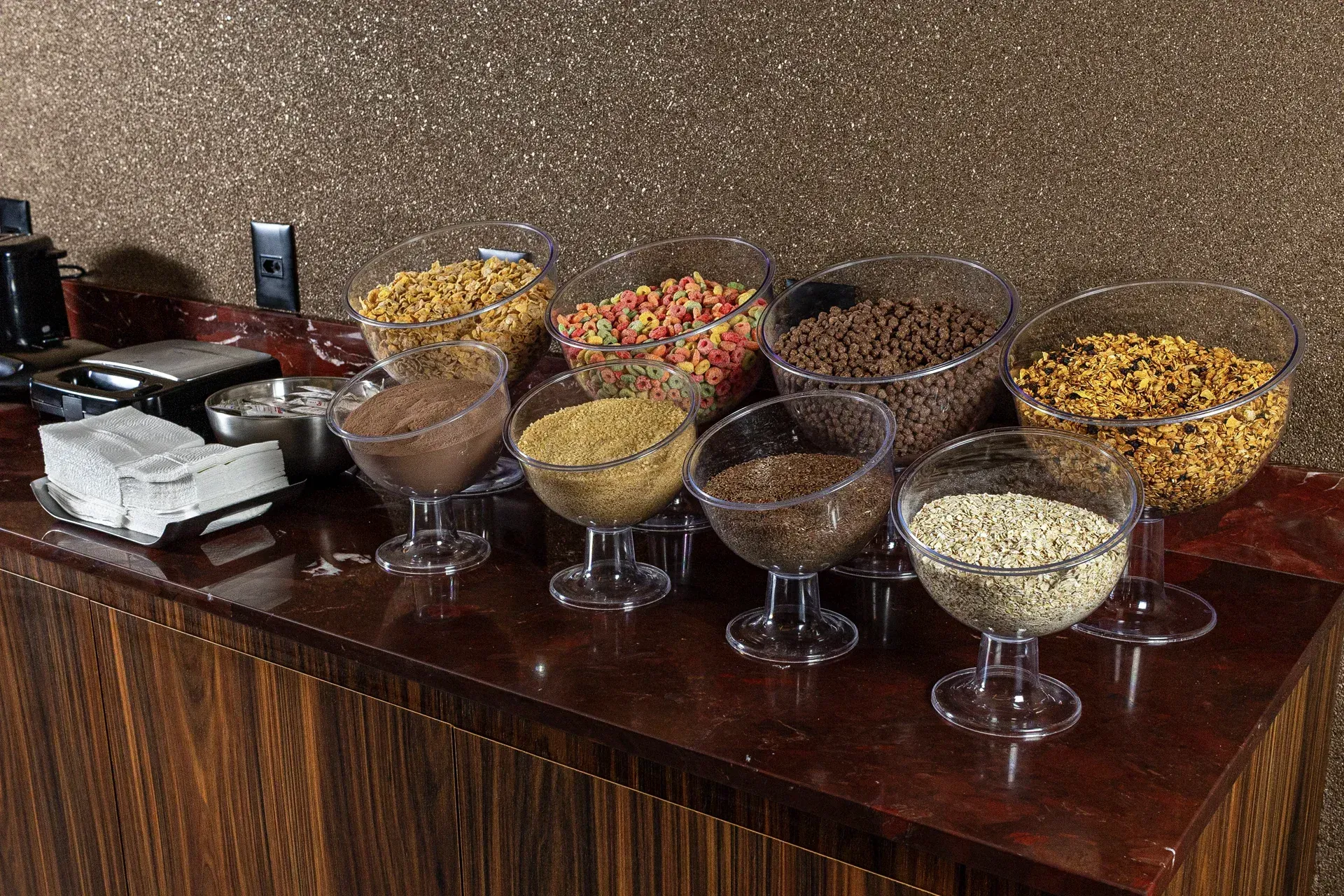 Uma mesa de bufê com tigelas de cereal e nozes.