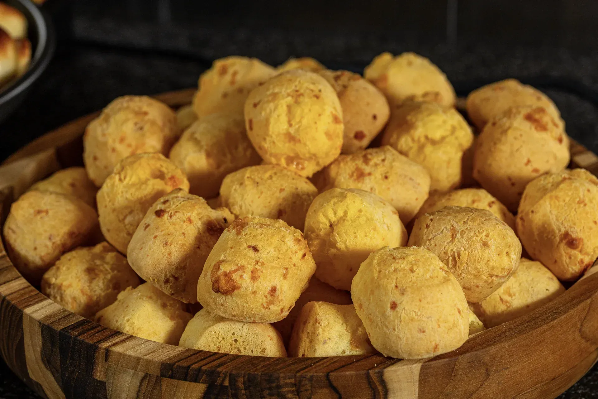Uma tigela de madeira cheia de bolinhas de queijo sobre uma mesa.