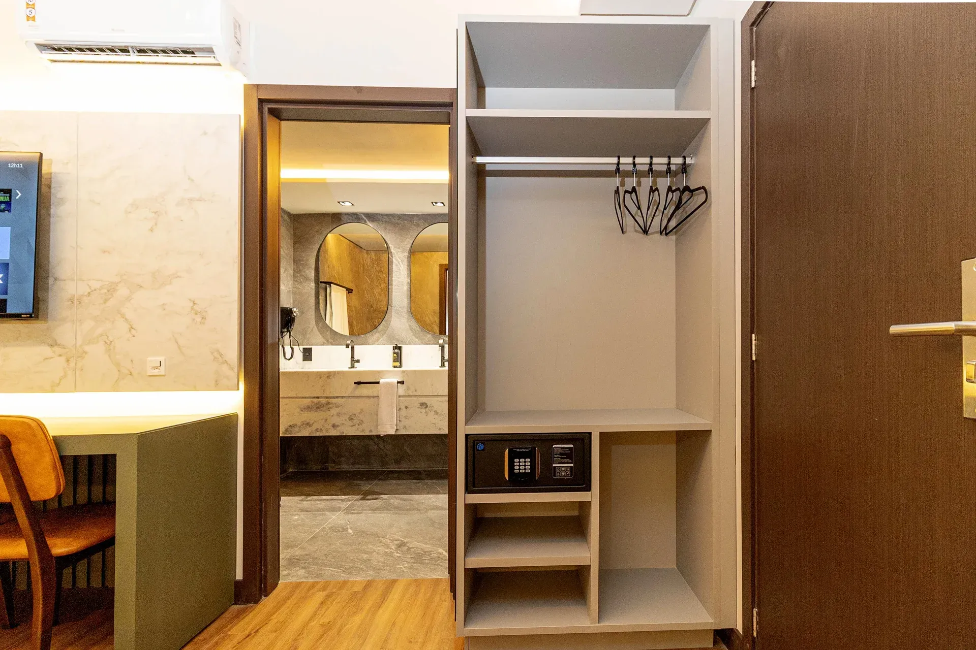 Um quarto de hotel com um armário e uma porta que levava a um banheiro.