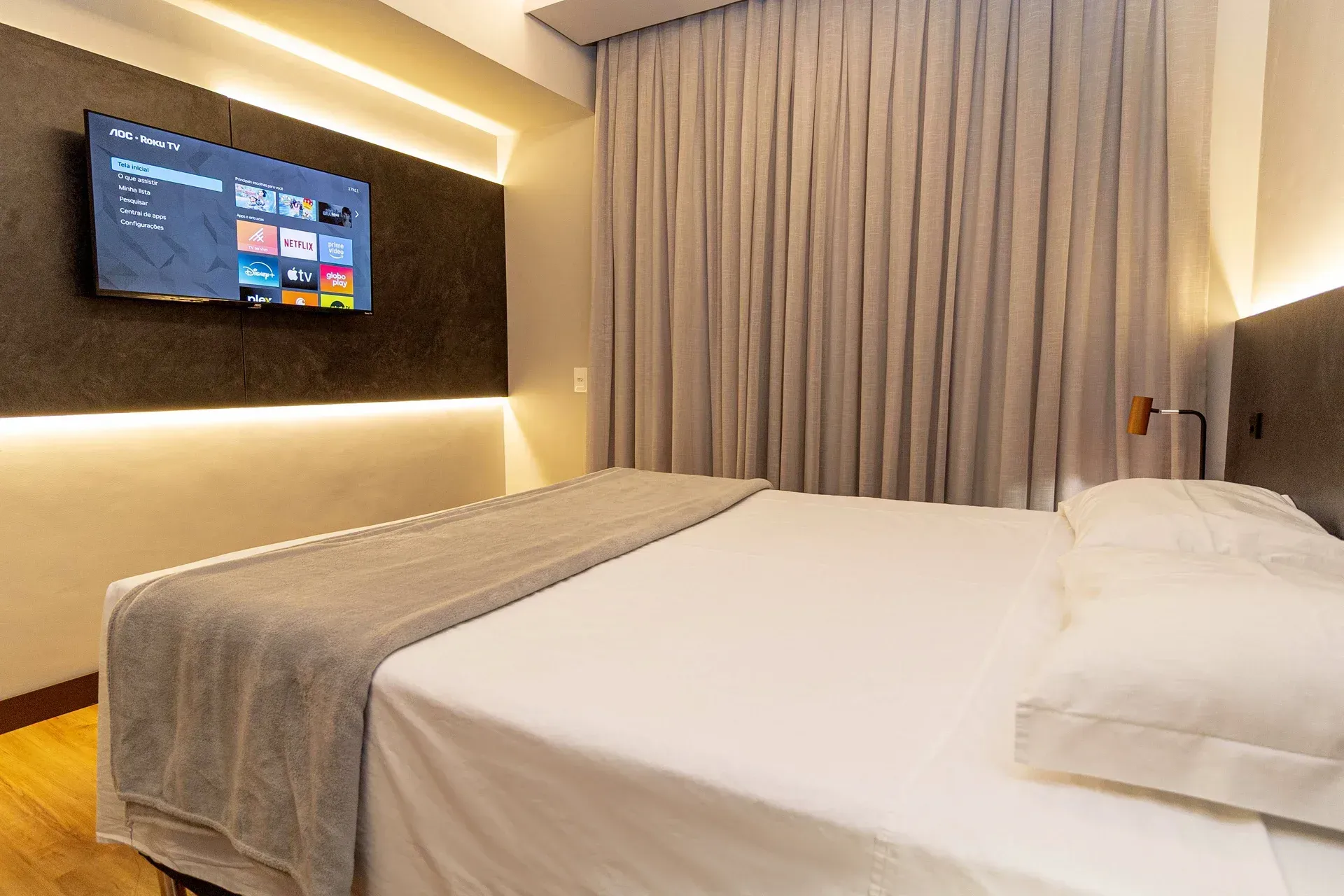Um quarto de hotel com uma cama grande e uma TV de tela plana na parede.