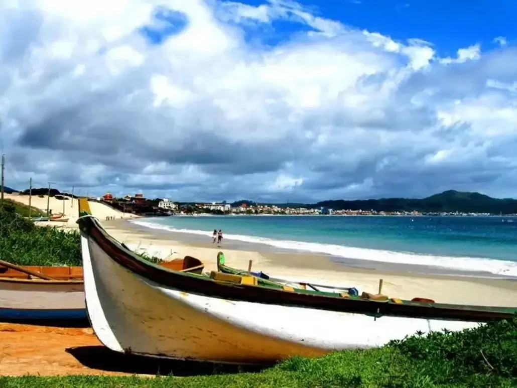 um barco parado em uma praia com uma cidade ao fundo