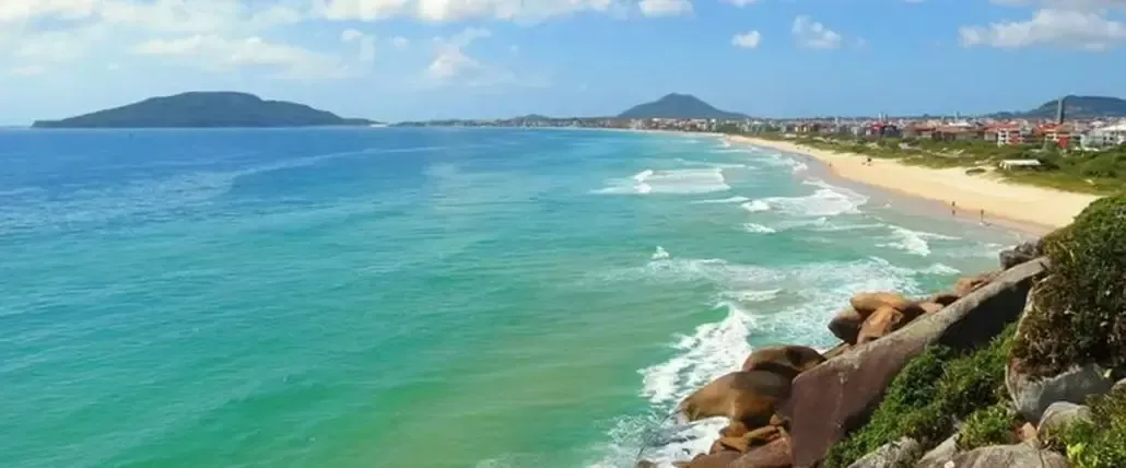 uma vista de uma praia a partir de uma falésia com uma montanha ao fundo.