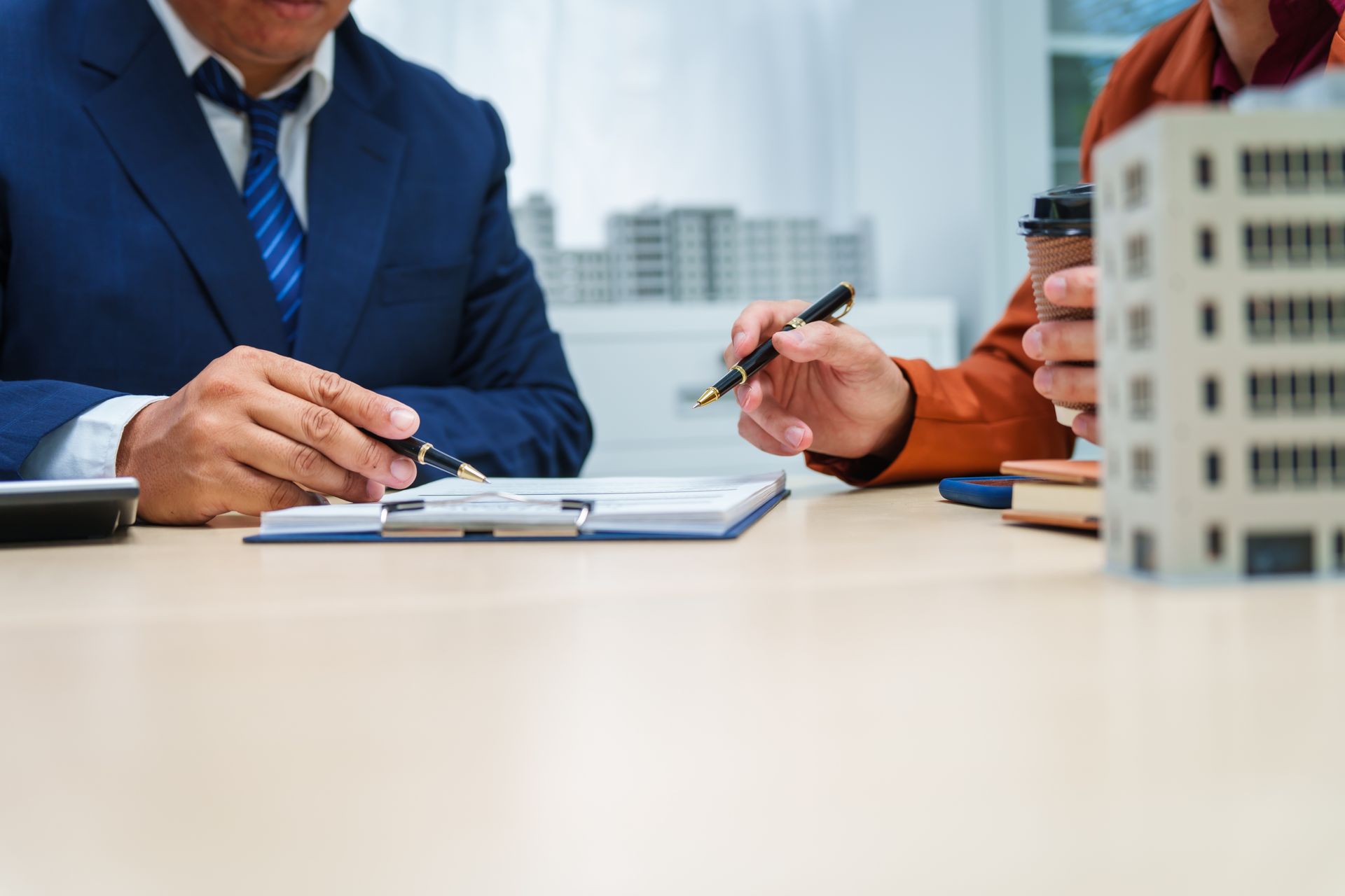Businesspeople signing documents at a conference table in an office with a city view