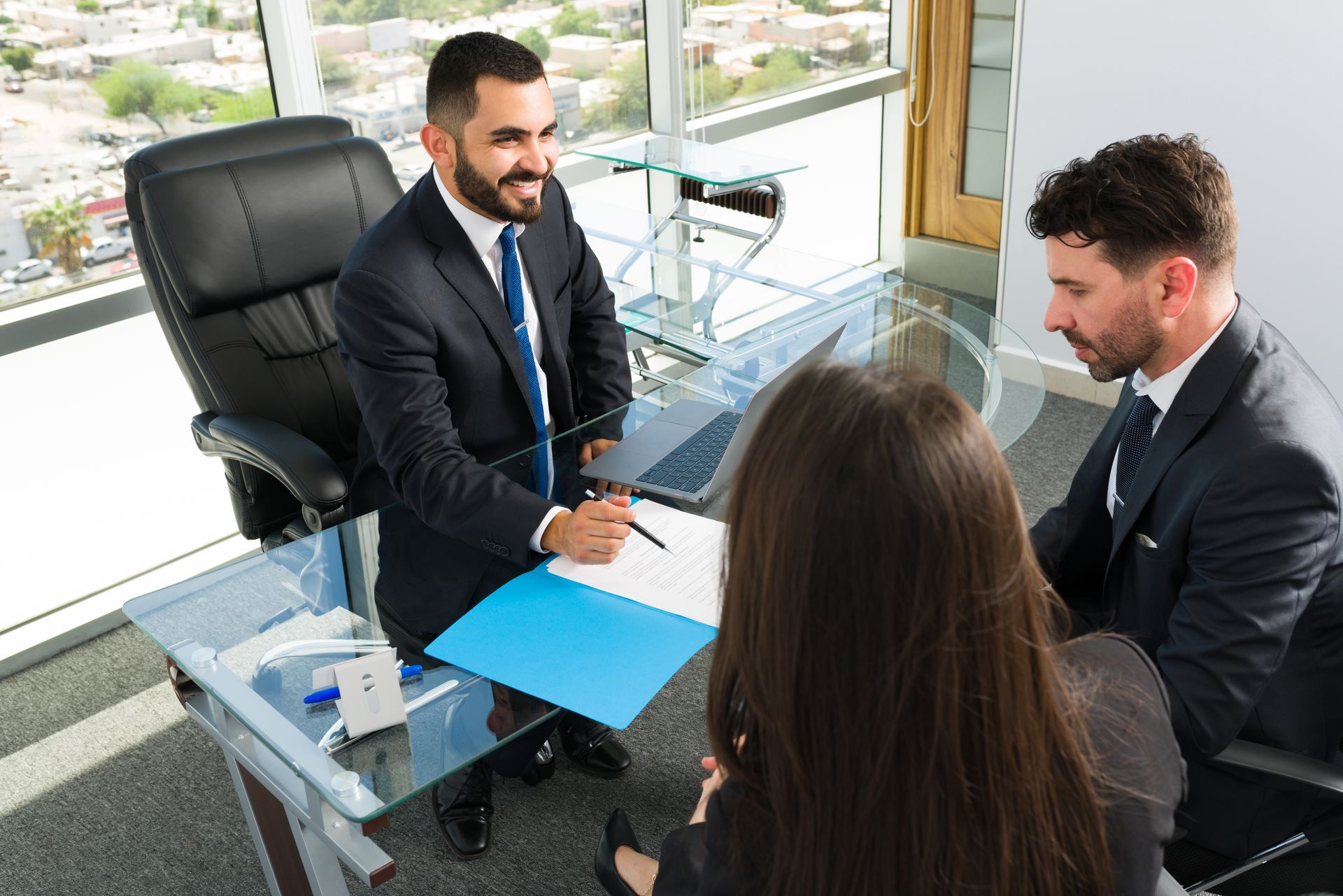 Businesspeople signing documents at a conference table in an office with a city view