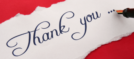 A pen is writing the word thank you on a piece of paper