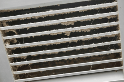 A close up of a dirty air vent on a wall.