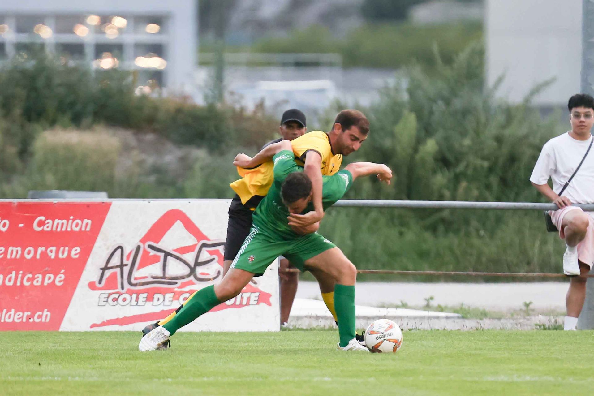 Deux hommes jouent au football devant un panneau indiquant aide