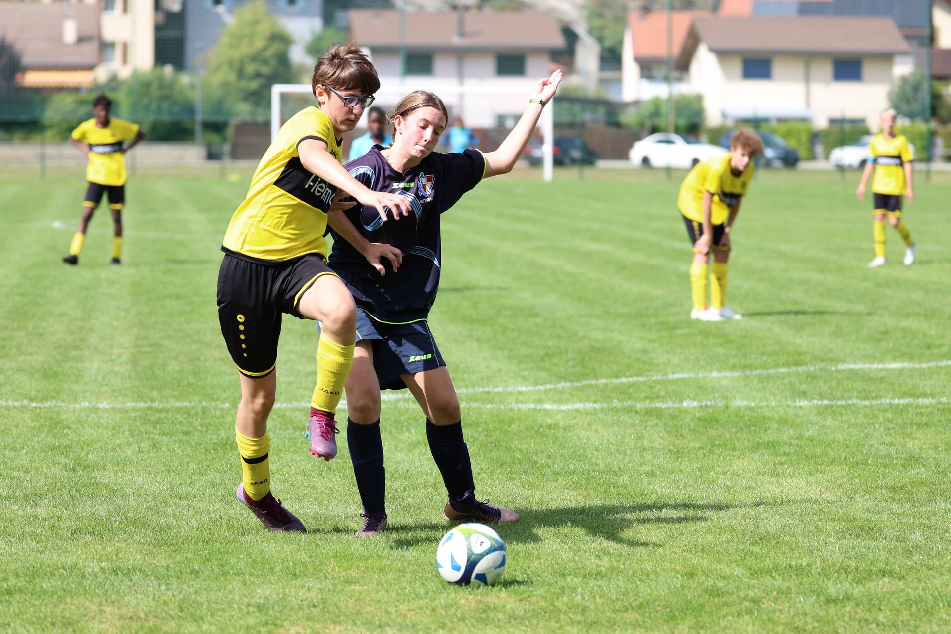 Deux joueurs de football se battent pour le ballon sur un terrain.