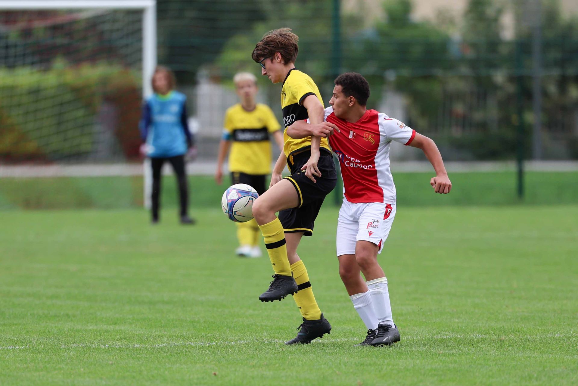 Deux jeunes hommes jouent au football sur un terrain.