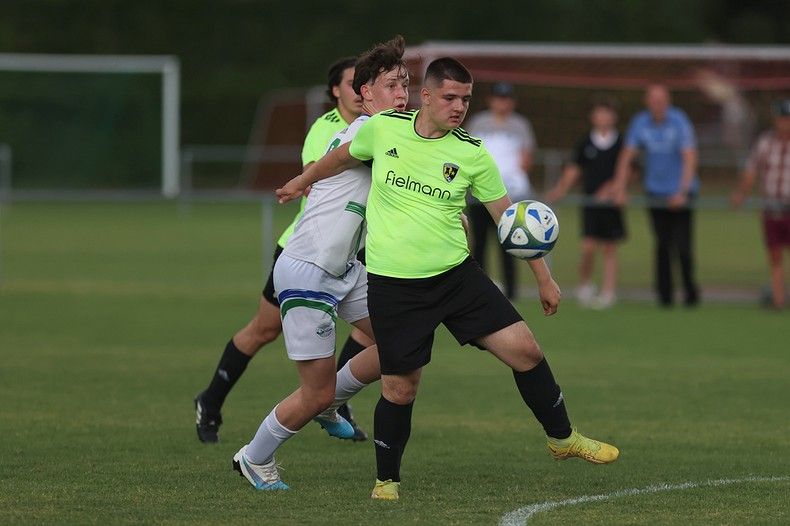 Un groupe de jeunes hommes jouent au football sur un terrain.
