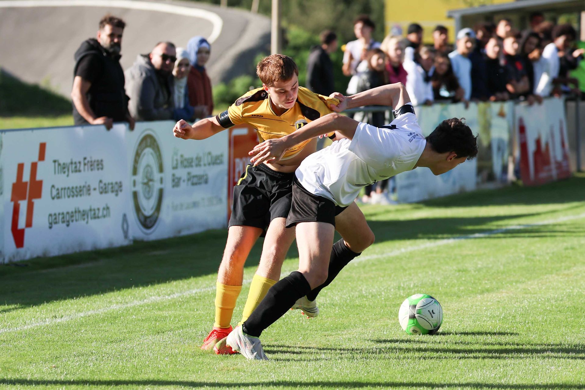 Deux joueurs de football se battent pour le ballon sur un terrain.