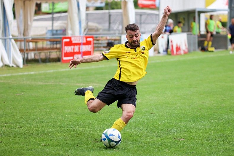 Un homme frappe un ballon de football sur un terrain.