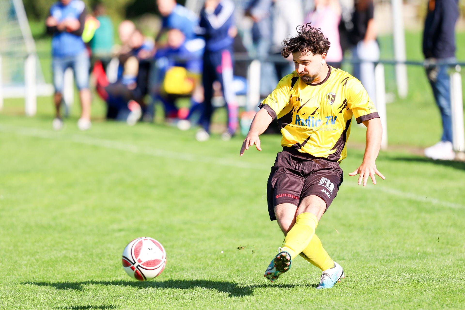 Un homme frappe un ballon de football sur un terrain.