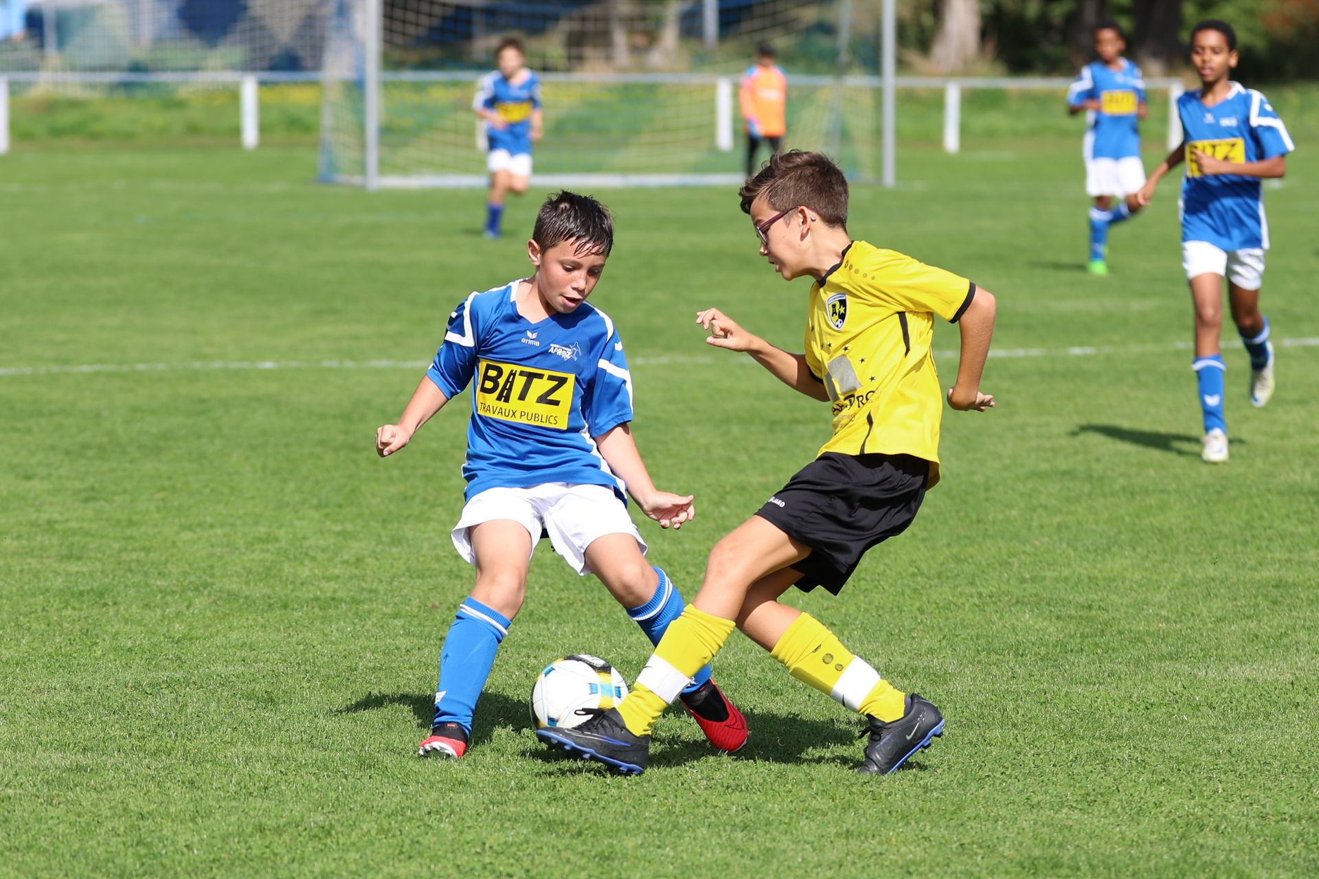 Deux jeunes garçons jouent au football sur un terrain.