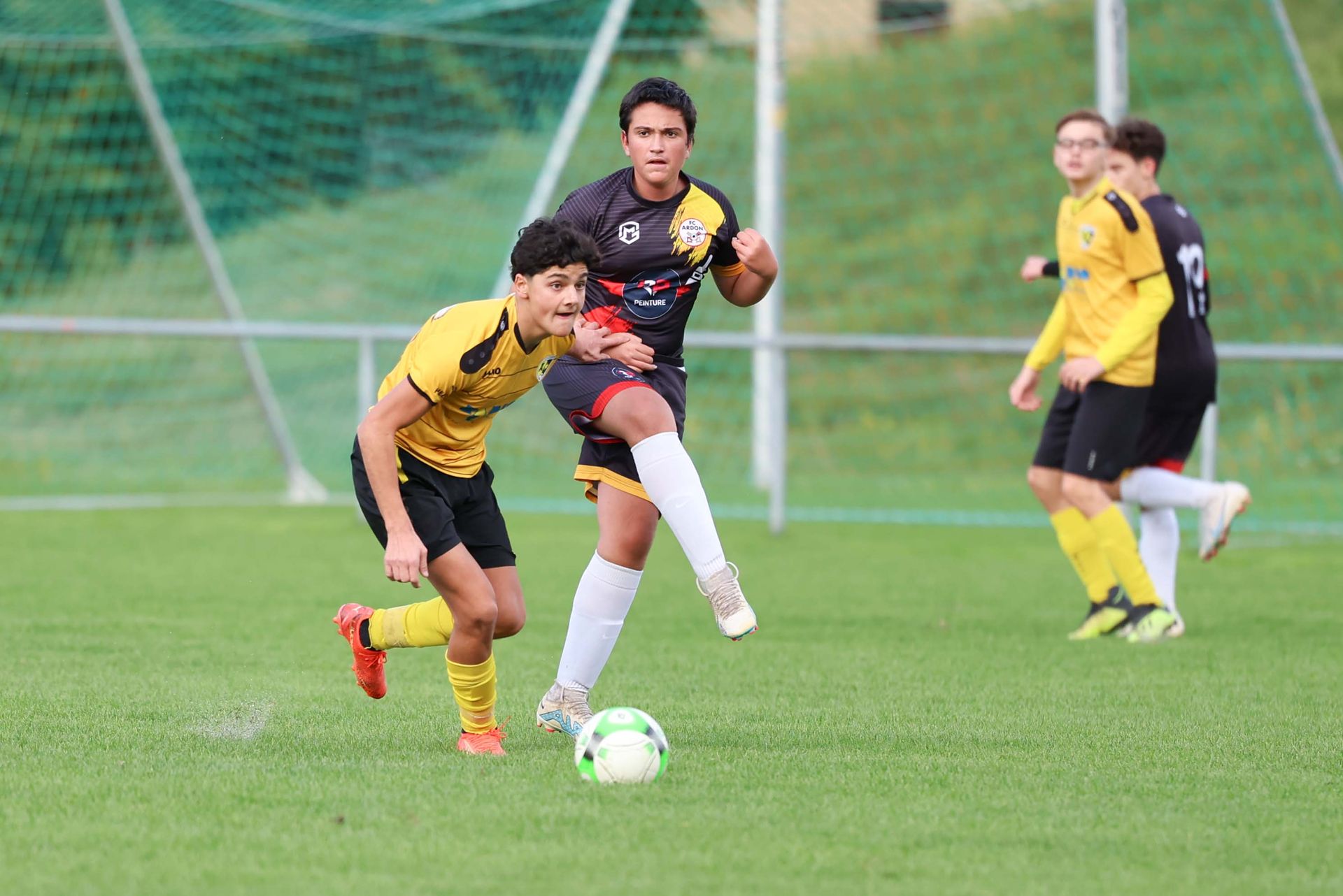 Un groupe de jeunes hommes jouent au football sur un terrain.