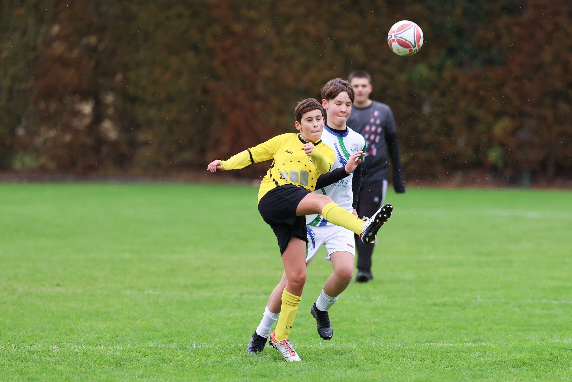 Un groupe de jeunes garçons jouent au football sur un terrain.