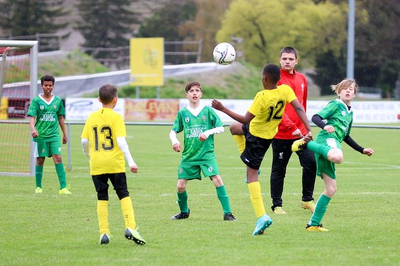 Un groupe de jeunes garçons jouent au football sur un terrain.
