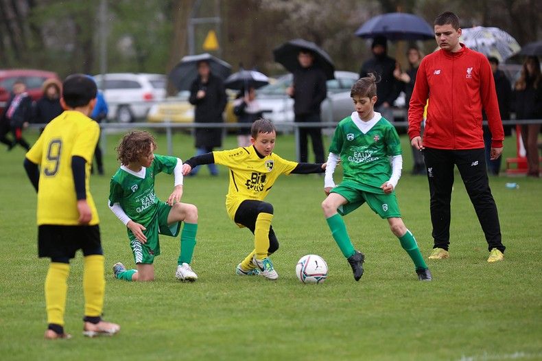 Un groupe de jeunes garçons jouent au football sur un terrain.