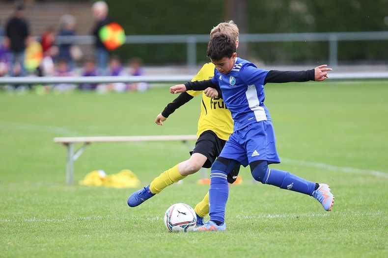 Deux jeunes garçons jouent au football sur un terrain.