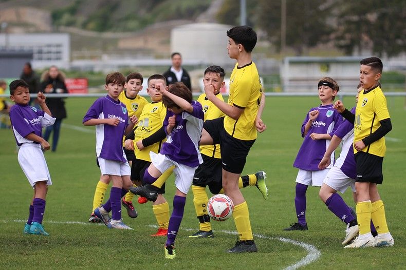 Un groupe de jeunes garçons jouent au football sur un terrain.